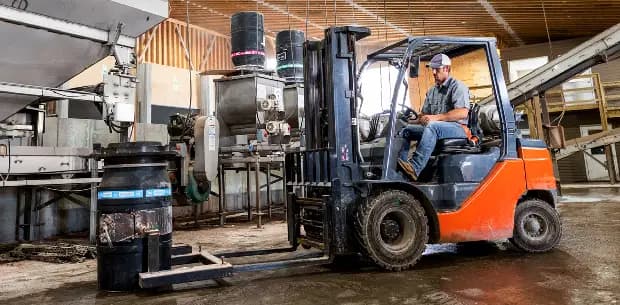 forklift in a factory preparing to lift a barrel